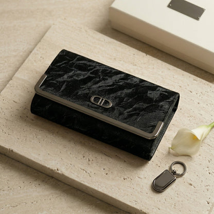 Black textured wallet with a keychain on a light surface